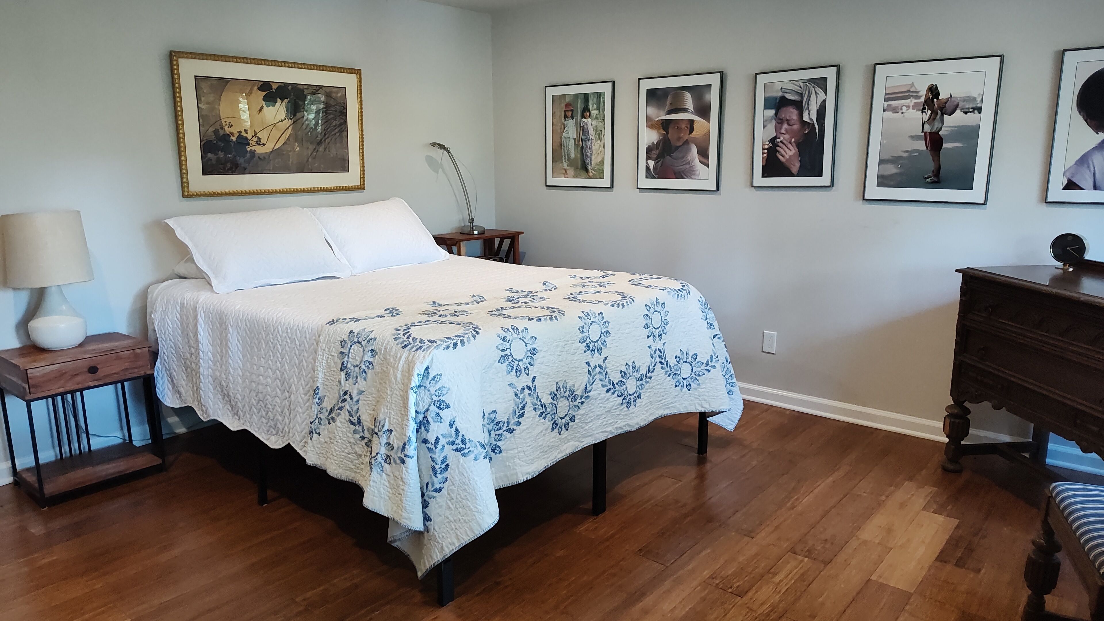 Une chambre à coucher comprenant un lit, une table de chevet, une commode et un mur orné de tableaux.