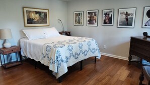A bedroom with a bed, a nightstand, a dresser, and a wall with framed pictures. - Spacious Lakeside Hideaway (Newtown)