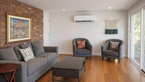 A modern living room with a grey sofa, two armchairs, a coffee table, and a large window providing natural light. - Spacious Lakeside Hideaway (Newtown)