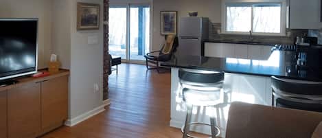 A modern kitchen with a large island, bar stools, and a flat-screen TV.