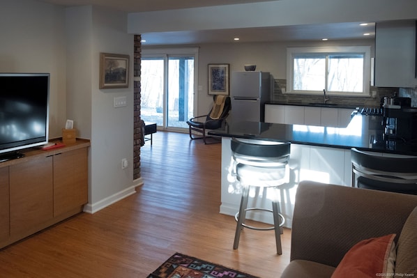 A modern kitchen with a large island, bar stools, and a flat-screen TV.
