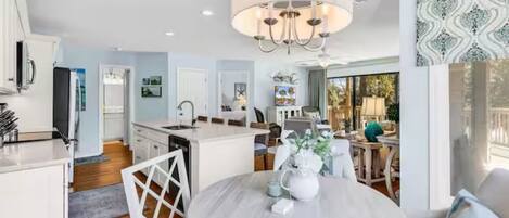 A modern kitchen with white cabinetry, a central island, and a chandelier.