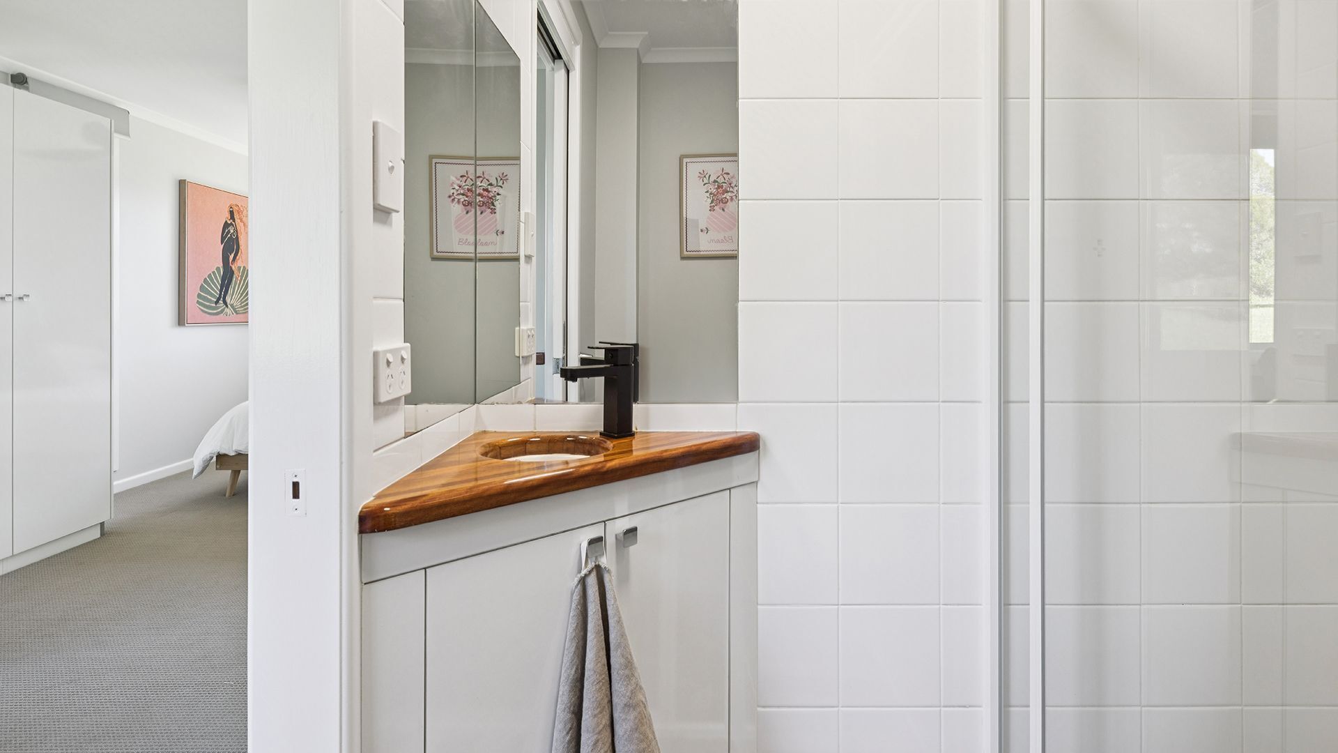 Un baño moderno con tocador de madera, azulejos blancos y un espejo grande.