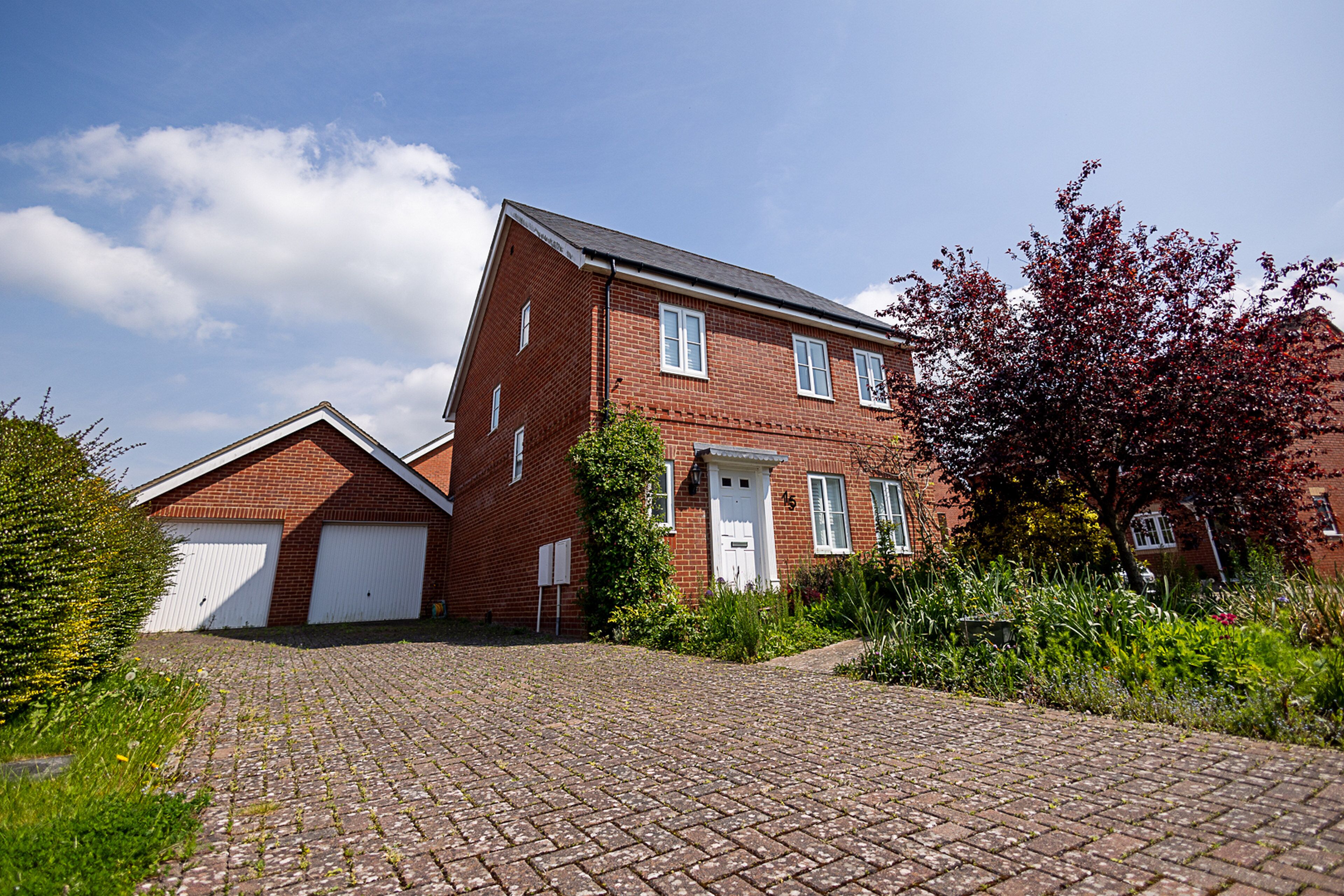 A two-story brick house with a paved driveway and a garage.