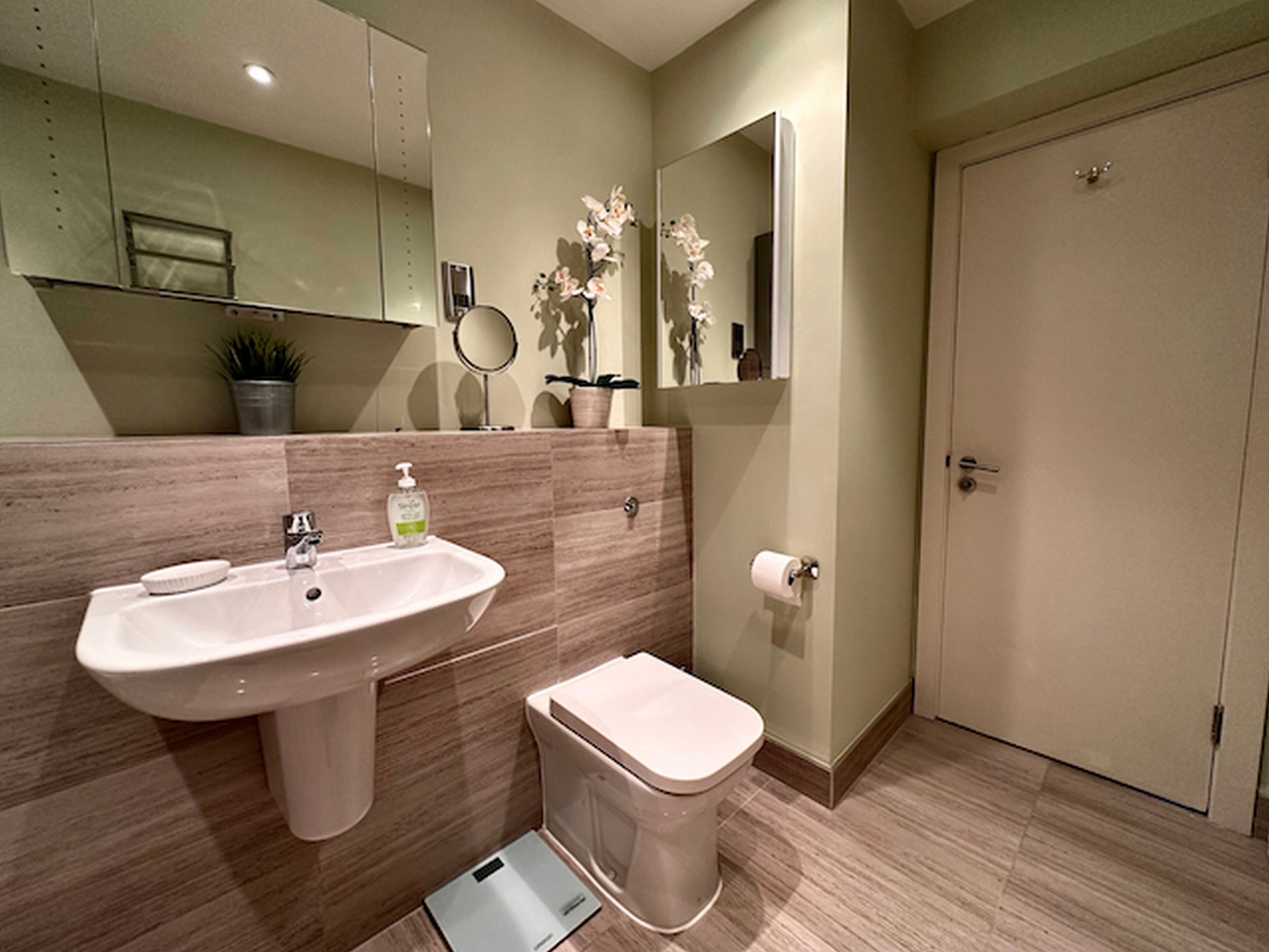 A modern bathroom with a sink, toilet, and a mirror.