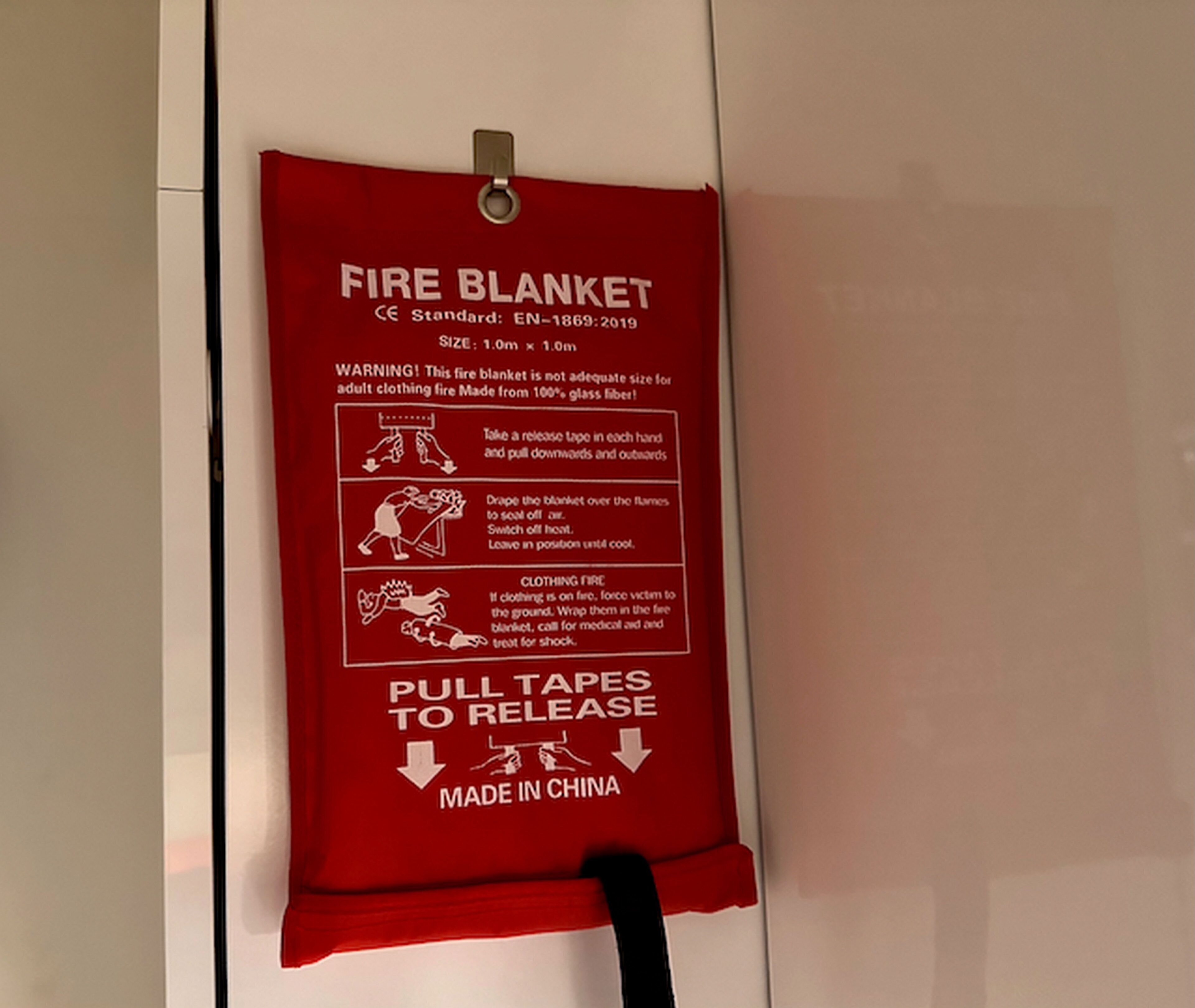 Una coperta antincendio appesa al muro, con istruzioni e informazioni sulla sicurezza.