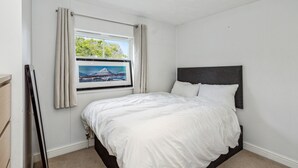 Quarto com cama, janela com vista e cortina.