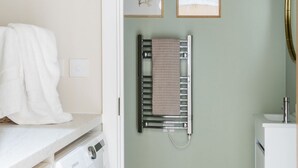 Ein Waschbereich mit Waschmaschine, Wäscheständer und einem Handtuch an der Wand.