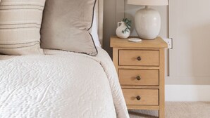 Ein Schlafzimmer mit einem Bett, Kissen, einem Nachttisch mit Lampe und einem Wandbild.