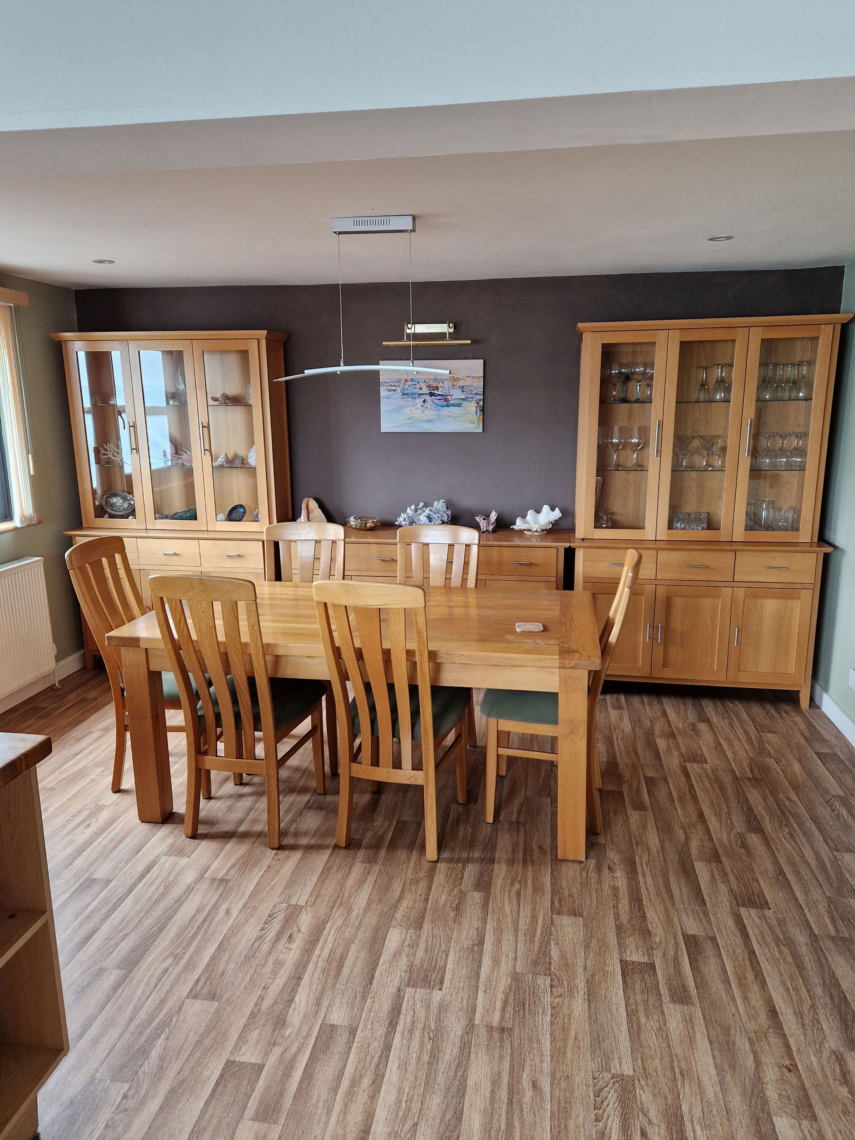 A dining area with a wooden table and chairs, flanked by wooden cabinets with glass doors.