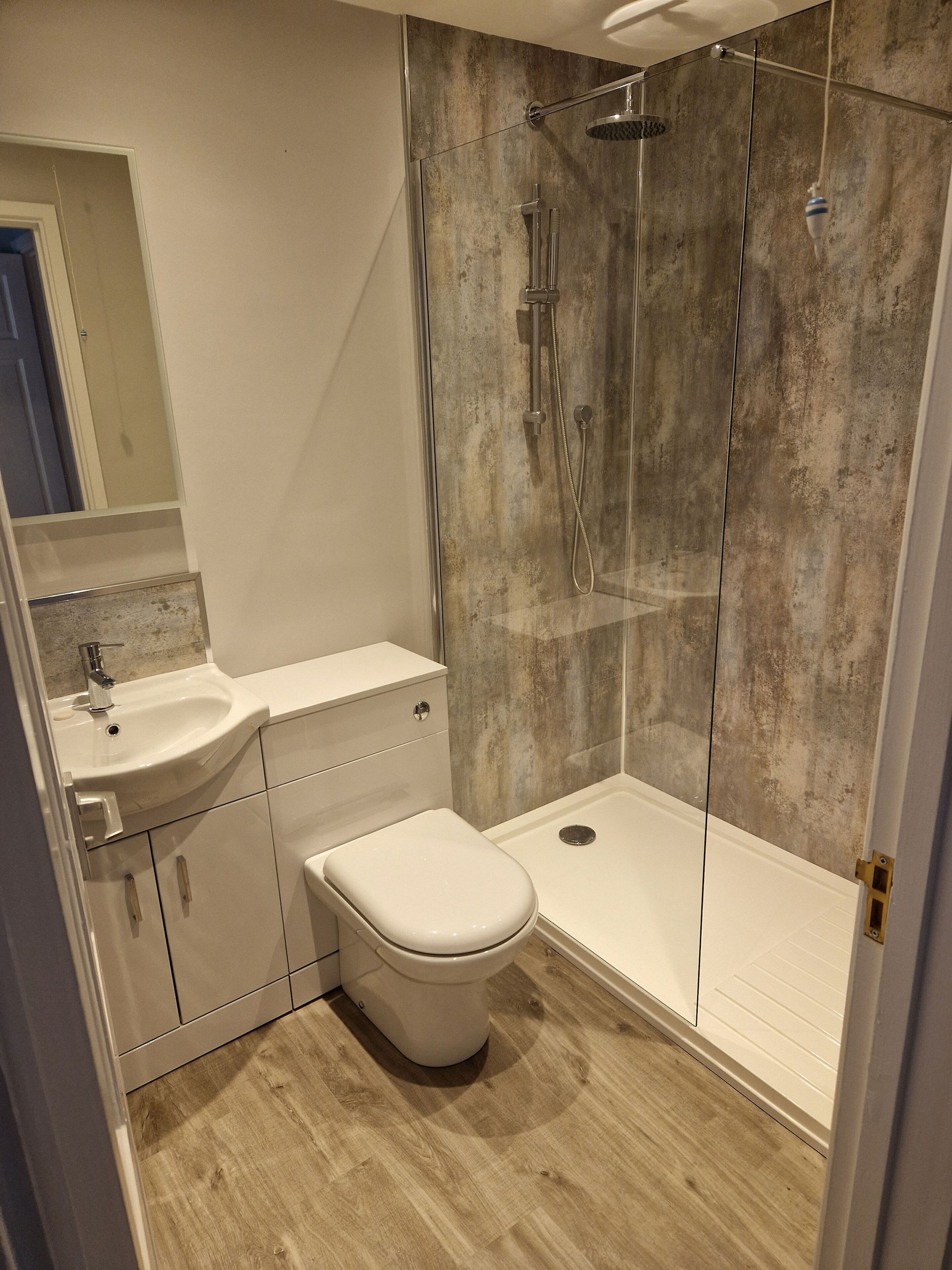 Een moderne badkamer met een douchecabine van glas, een wit wastafelmeubel en een toilet.