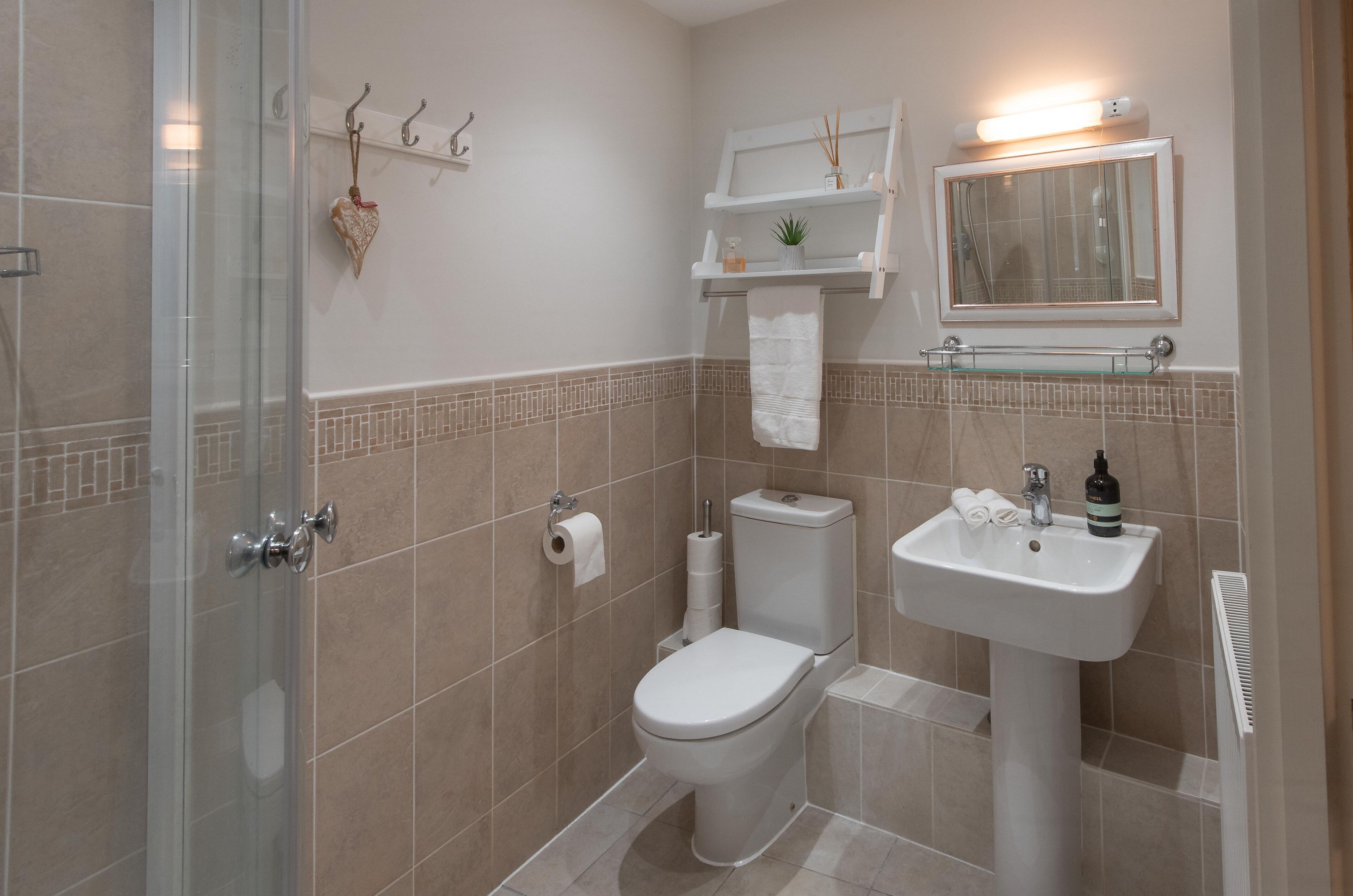 Een badkamer met een douchecabine van glas, een toilet, een wastafel en een spiegel.