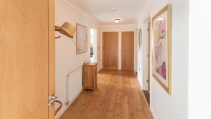 Un couloir doté d’un plancher en bois, d’un radiateur et d’une petite table en bois.