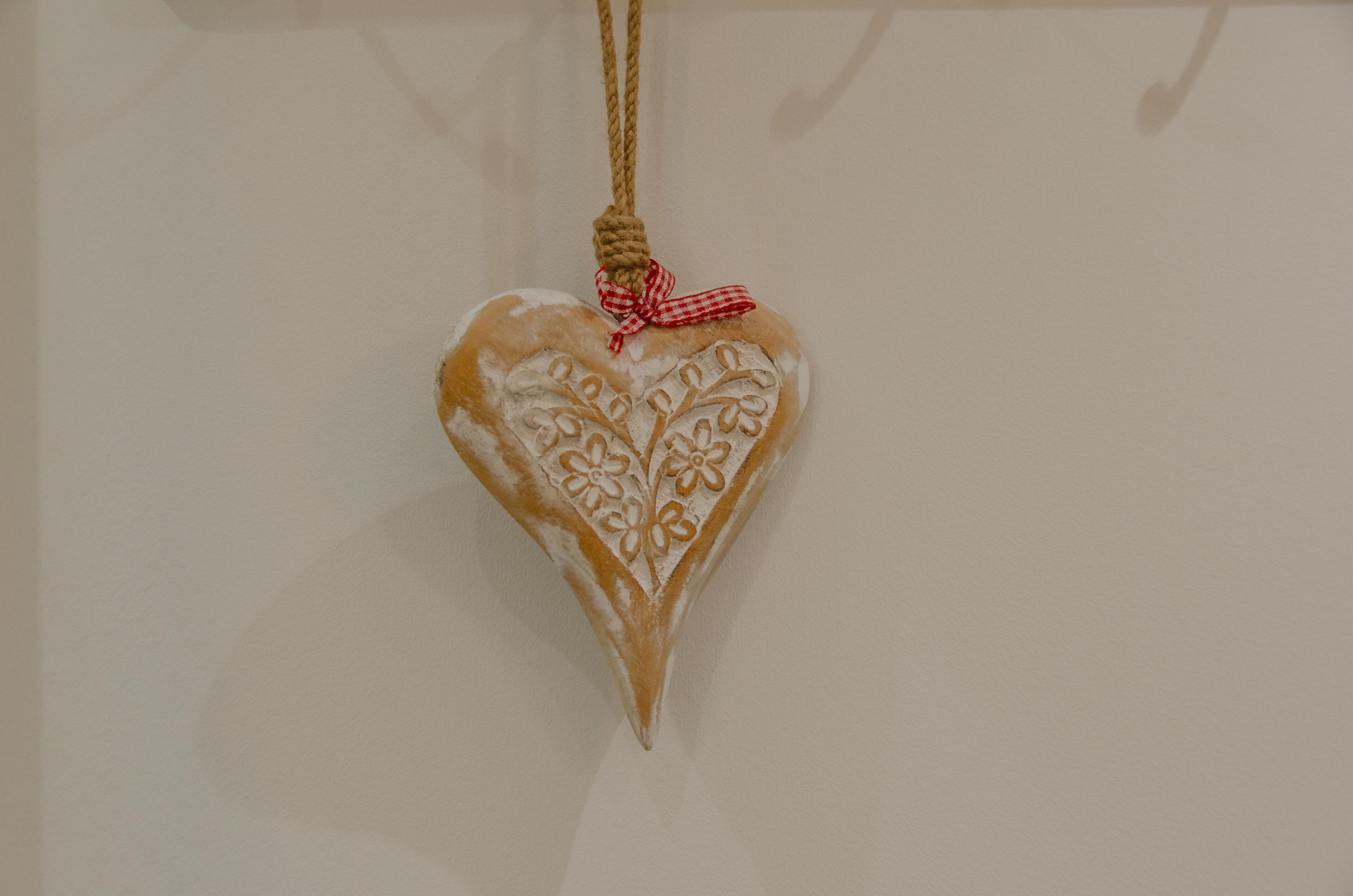 A heart-shaped ornament with a rope and a checkered bow.