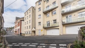 Une rue bordée d’immeubles à plusieurs étages, avec un passage piéton et un véhicule stationné.