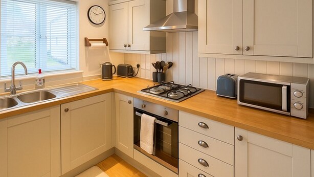 A kitchen with a sink, stove, microwave, and cabinets. - Elegant 2Bd Townhouse In Thirsk: Cozy & Stylish (Thirsk)