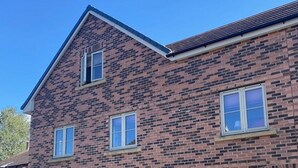 A two-story brick building with a flat roof, a front door, and a small porch area. - Elegant 2Bd Townhouse In Thirsk: Cozy & Stylish (Thirsk)