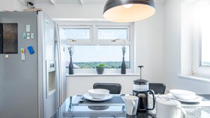 A modern kitchen with a granite countertop, a coffee maker, and a view of the countryside through the window. - 2Bd House With Stunning Views Of The Sea And Gower (Killay)