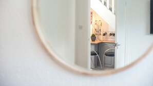 A view through a circular window into a room with a wooden table, chairs, and a plant. - 2Bd House With Stunning Views Of The Sea And Gower (Killay)
