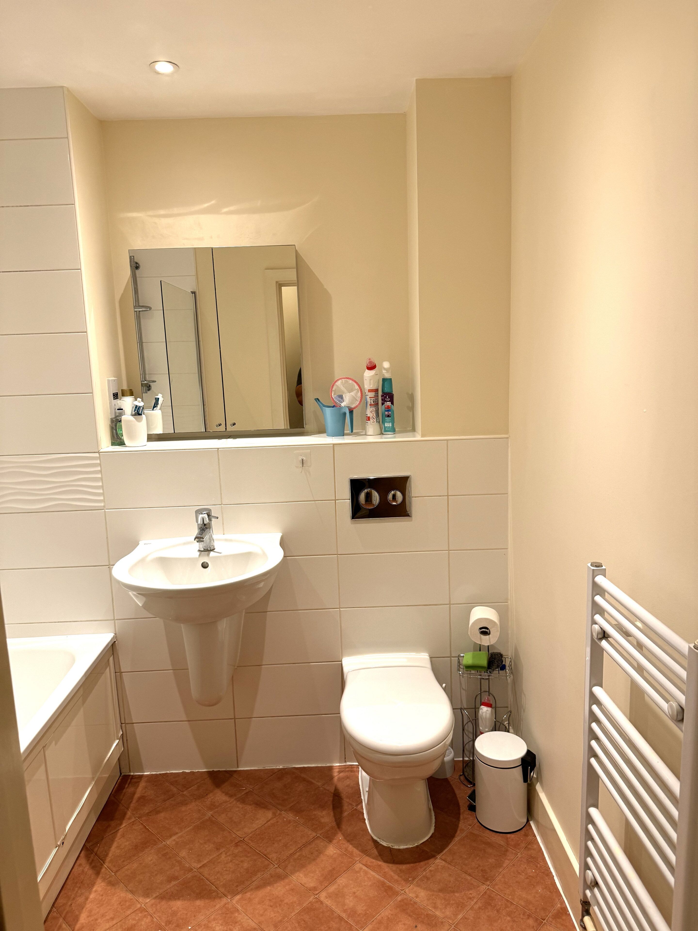A bathroom with a sink, toilet, mirror, and a towel rack.