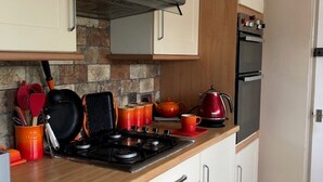 A compact kitchen with white cabinets, a gas stove, and a built-in oven. - Cosy House In Lovely Market Town (Newport)