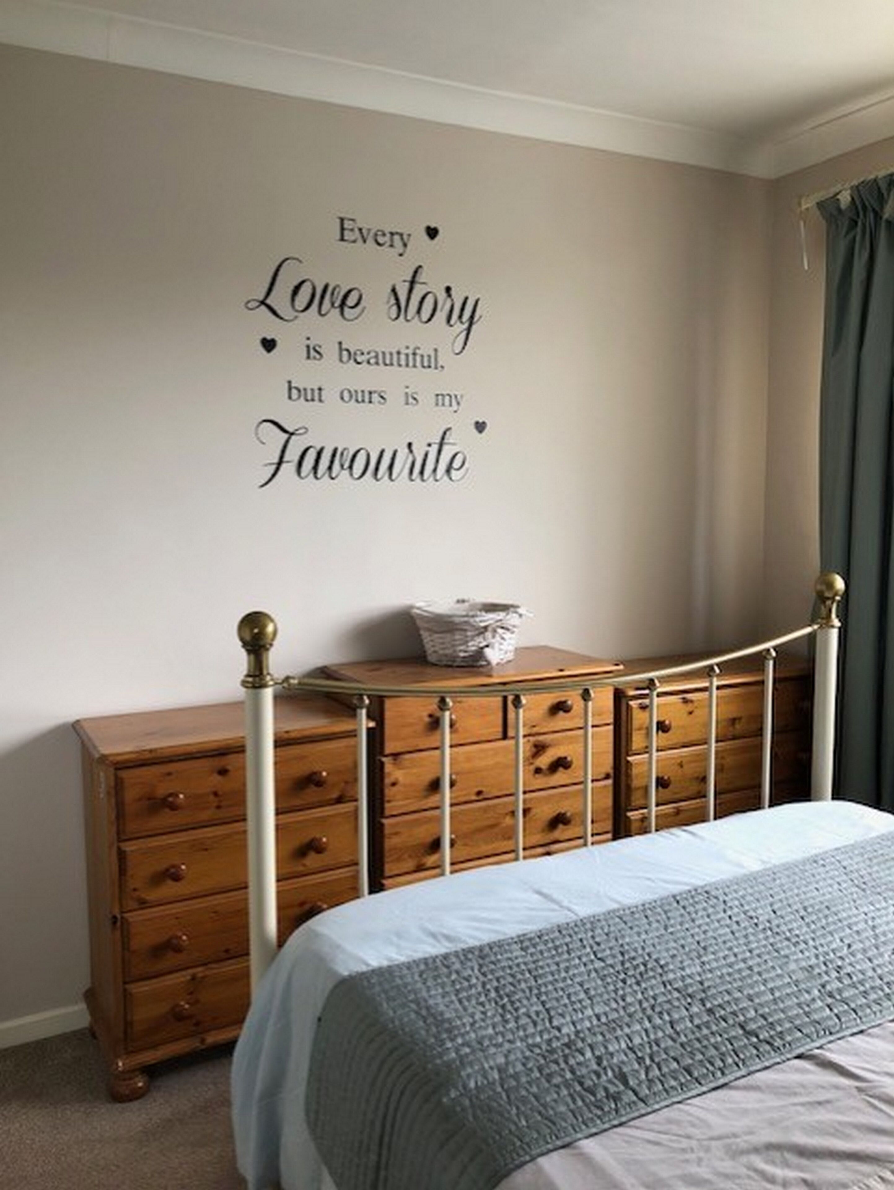 A bedroom with a bed, a dresser, and a wall with a decorative quote.