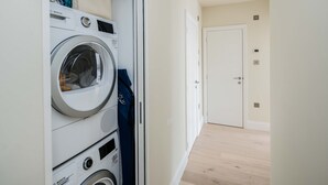 Una sala de lavandería con lavadoras Bosch apiladas y una puerta que da a otra habitación.