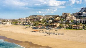 Une station balnéaire dotée de villas en bord de mer, d’une plage de sable et offrant une vue sur les montagnes.