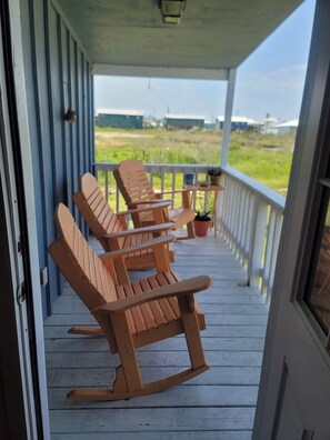 A porch with rocking chairs and a potted plant. - Charming 2-bedroom Camp with Private Pier (Grand Isle)