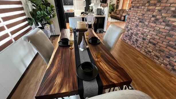 Un comedor con una larga mesa de madera, camino de mesa a rayas blancas y negras, y sillas a juego.