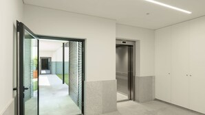 Ein moderner Flur mit Glastür zu einem Innenhof, einem Glaselevator und mehreren Schränken.