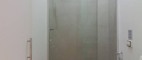 A compact bathroom with a glass-enclosed shower, a toilet, and a sink.