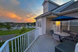 Eine Wohnterrasse mit Gartenmöbeln und Blick auf die Nachbarschaft bei Sonnenuntergang.