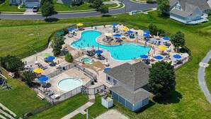 A large outdoor swimming pool with multiple lanes, surrounded by lounge chairs and umbrellas. - Spacious Family-Friendly Condo Near Bethany Beach (Ocean View)