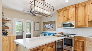 Una cocina con armarios de madera, una isla central, electrodomésticos de acero inoxidable y un ventilador de techo.