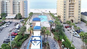 Ein Hochhaus-Hotel mit Pool, Parkplatz und Blick auf den Strand.
