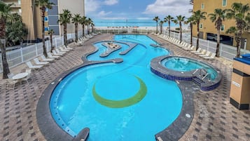 A swimming pool with a circular design, surrounded by lounge chairs and palm trees, with a view of the beach and ocean in the background.