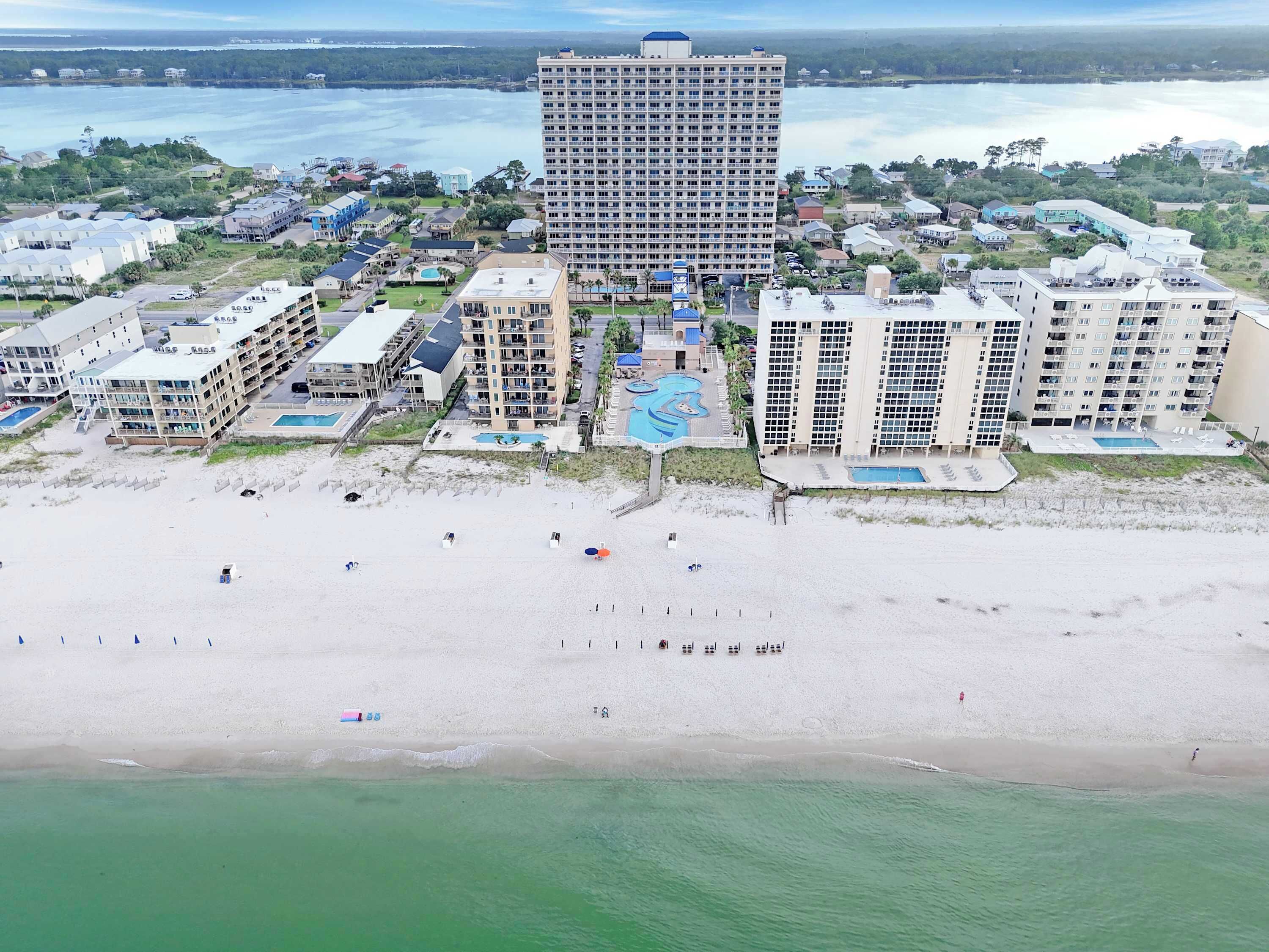 Ein Küstenresort mit mehreren Hochhäusern, einem Sandstrand und einem großen Schwimmbecken.