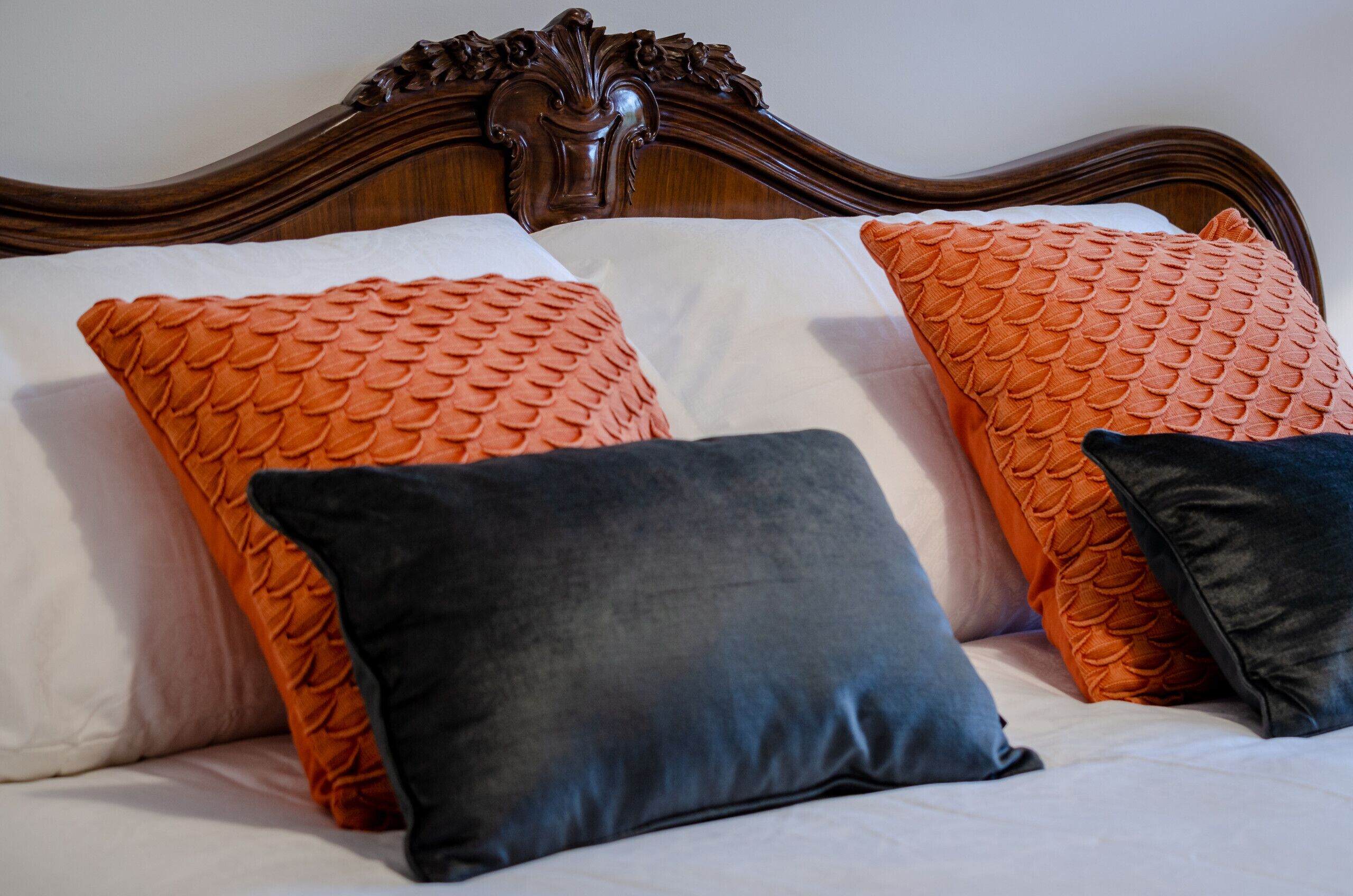 Ein Bett mit zwei orangefarbenen und einem schwarzen Kopfkissen.