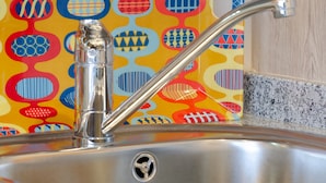 A kitchen sink with a modern faucet and a colorful backsplash.