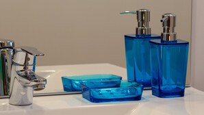 A bathroom sink with a chrome faucet, two blue glass soap dispensers, and a blue glass soap dish.