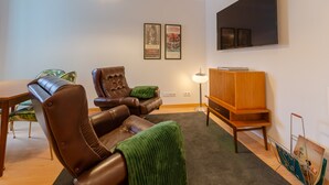 A modern living room with a leather sofa, a wooden cabinet, a flat-screen TV, and framed posters on the wall. - Setubal Boutique Apartments III by Homing (Setubal)