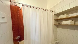 A bathroom with a shower curtain, a bathtub, a toilet, and a sink. - Rent Up-Monoambiente clásico en Recoleta (Buenos Aires)