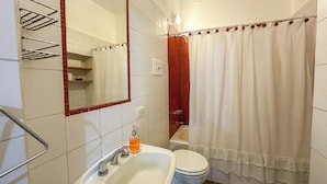A bathroom with a white sink, a mirror, a toilet, and a shower curtain. - Rent Up-Monoambiente clásico en Recoleta (Buenos Aires)