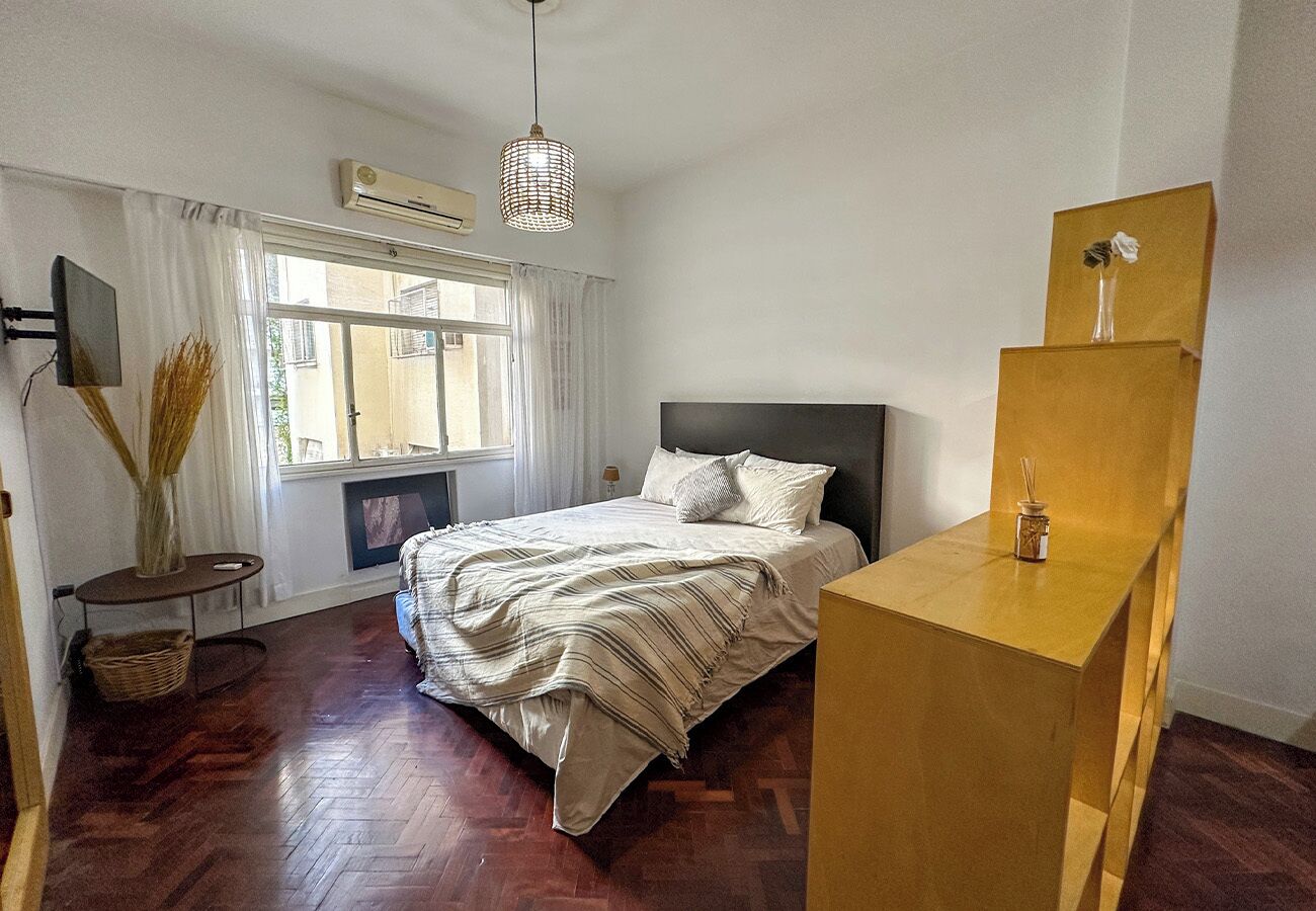 A bedroom with a bed, bedside table, and a window with curtains.