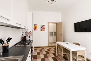 A compact kitchen with white cabinets, a gas stove, and a checkered floor. - BIG Milan Nest [Duomo-M4 Lin Aeroporto] (Milan)