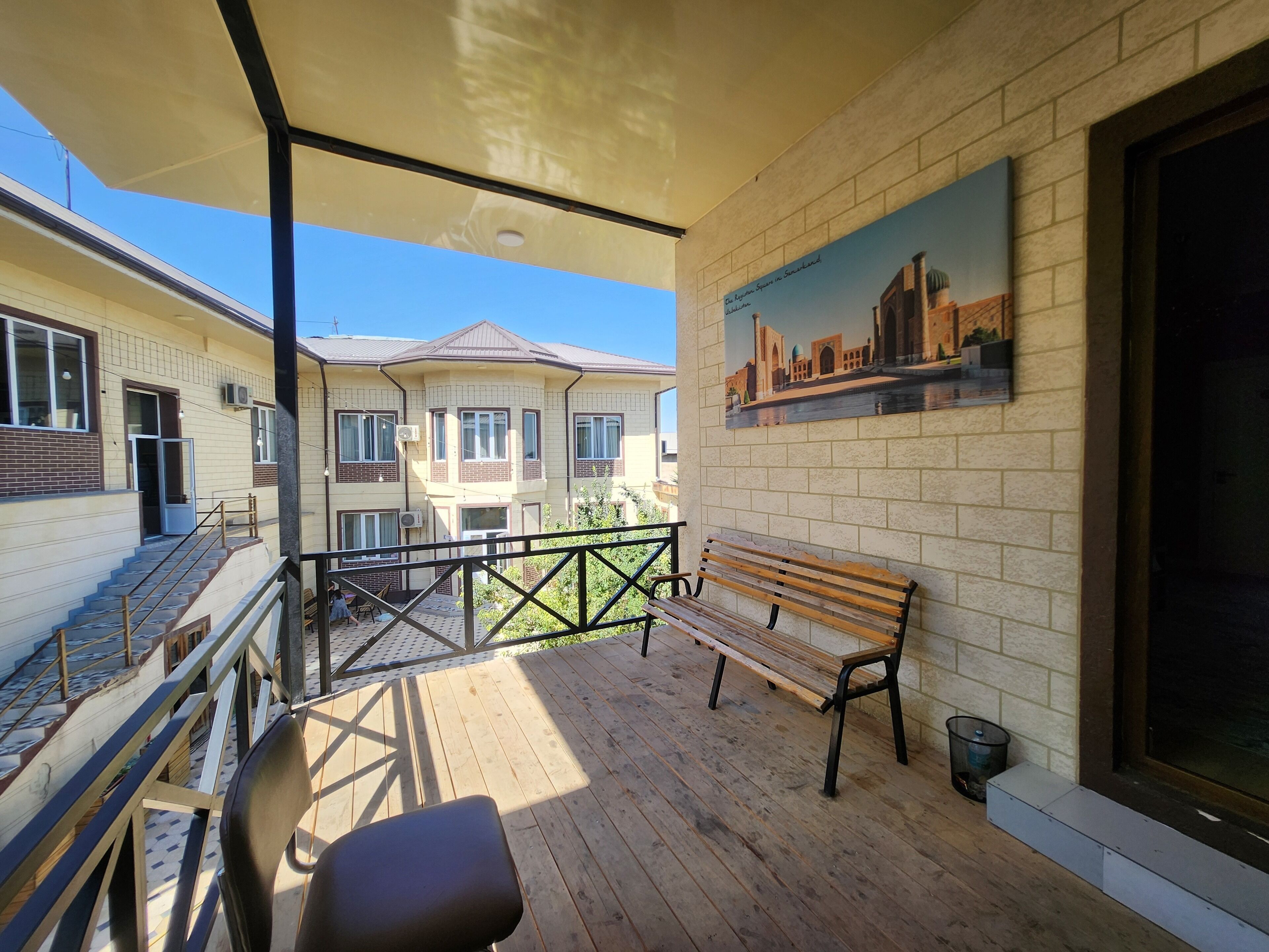 Un balcon avec un banc en bois, une chaise et une rambarde.