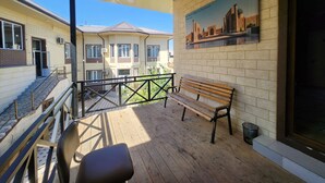 A balcony with a wooden bench, a chair, and a railing. - Enjoy your stay in nice place for big families and groups up to 15 guests (Tashkent)