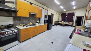 A kitchen with a gas stove, oven, and modern cabinetry. There is a dining area with a table and chairs. - Enjoy your stay in nice place for big families and groups up to 15 guests (Tashkent)