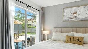 Una habitación de hotel con una cama grande, vistas al exterior, una almohada con la palabra 'Hello' y un cuadro de flores en la pared.